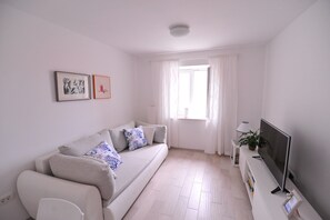 A modern living room with a sofa, a flat-screen TV, and a window with curtains. - A1 - luxury apartment in center, just 5 min from beach (Korčula)
