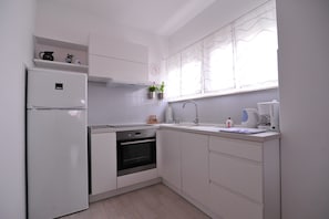 A modern kitchen with white cabinets, a built-in oven, a refrigerator, a sink, and a window with sheer curtains. - A1 - luxury apartment in center, just 5 min from beach (Korčula)