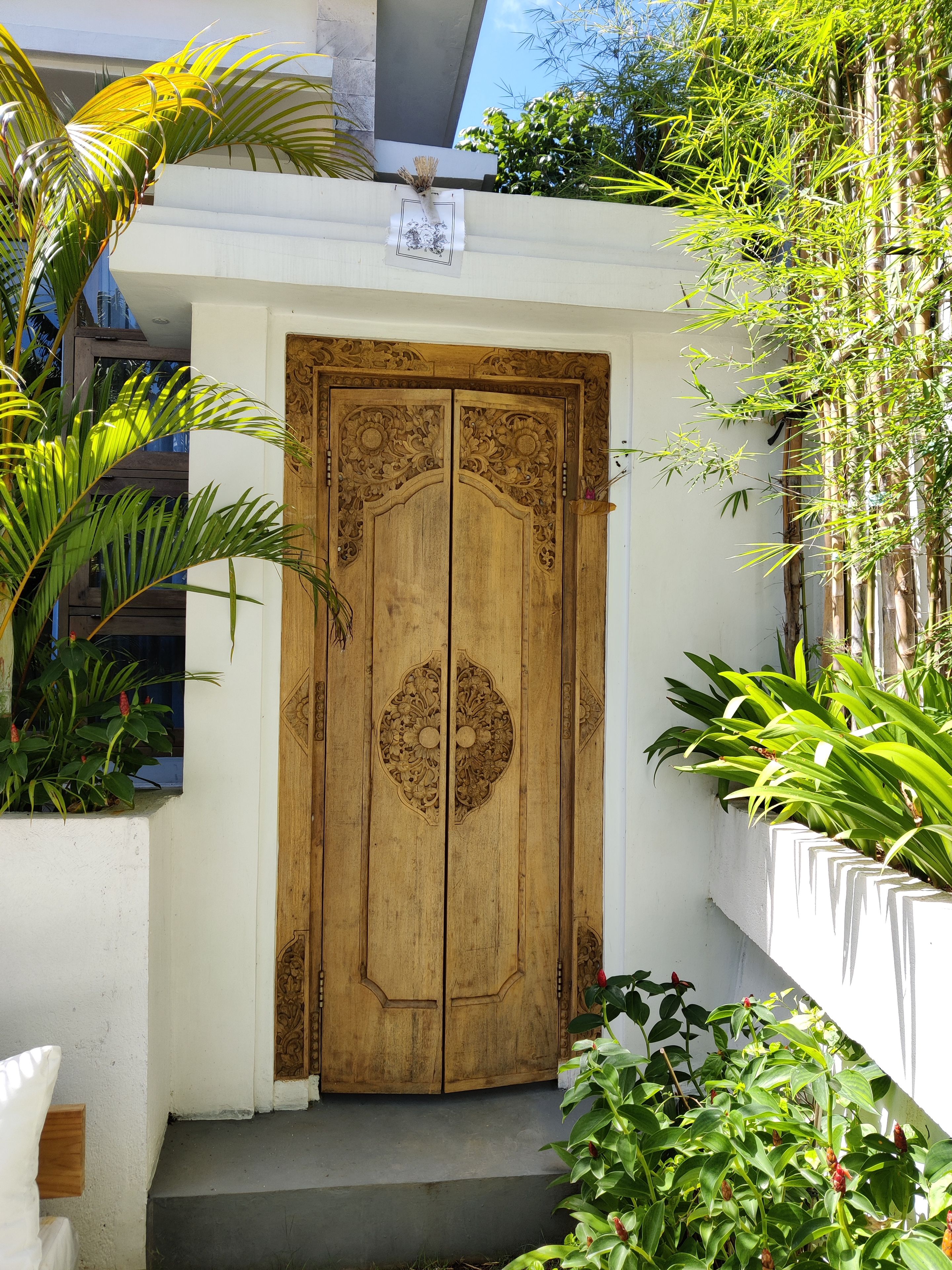 A wooden door with intricate carvings, a white wall, and a small step leading up to it.