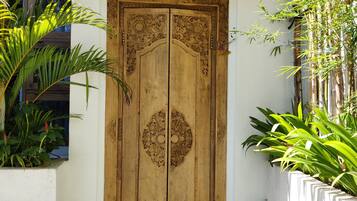 A wooden door with intricate carvings, a white wall, and a small step leading up to it.