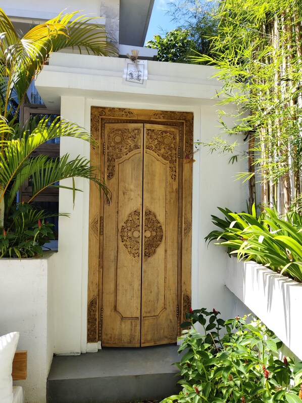 A wooden door with intricate carvings, a white wall, and a small step leading up to it.