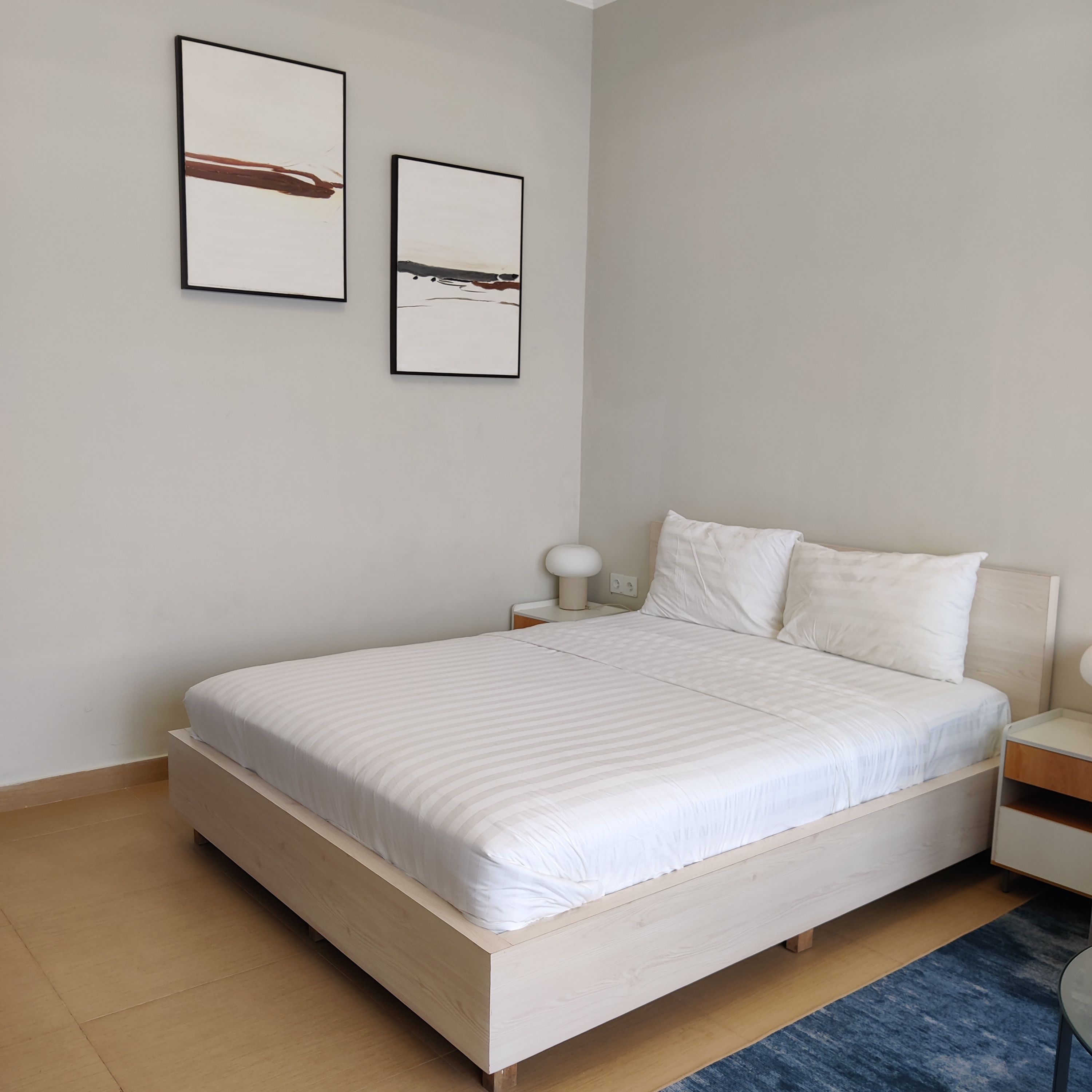 Ein Schlafzimmer mit einem Bett, Nachttischen und zwei Bildern an der Wand.