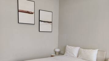 A bedroom with a bed, bedside tables, and two wall-mounted pictures.