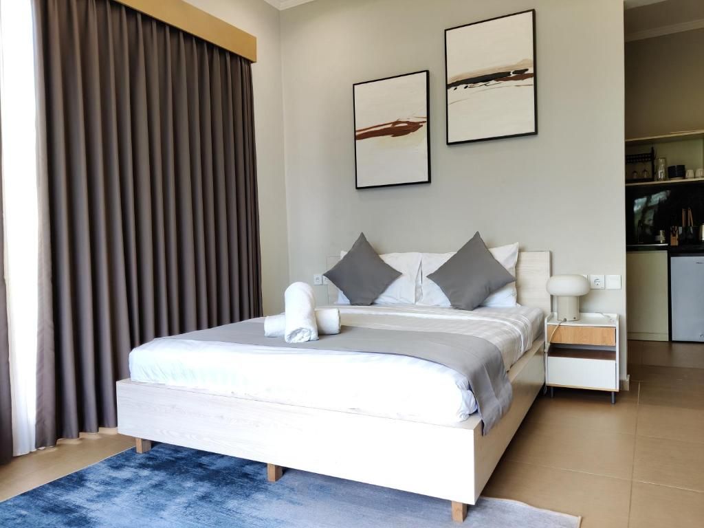 Un dormitorio moderno con una cama grande, una mesita de noche y una lámpara de noche. Hay dos obras de arte enmarcadas en la pared.
