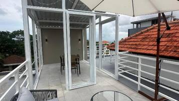 Un espacio de estar al aire libre cubierto con una mesa, sillas y un sofá, además de una gran sombrilla que proporciona sombra.
