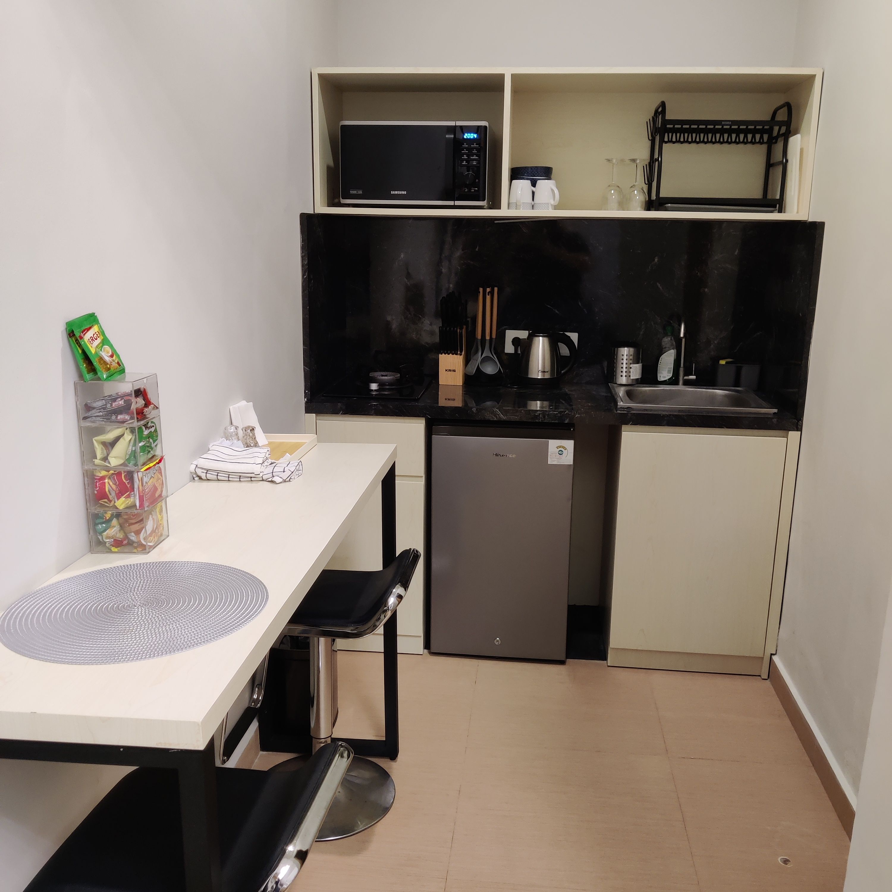 A compact kitchenette with a microwave, coffee maker, and sink.