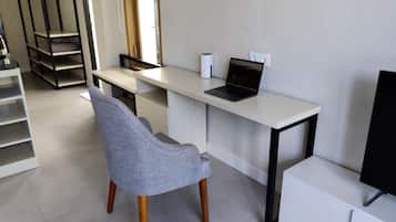 Ein moderner, minimalistischer Arbeitsraum mit einem weißen Schreibtisch, einem Laptop und einem grauen Stuhl.