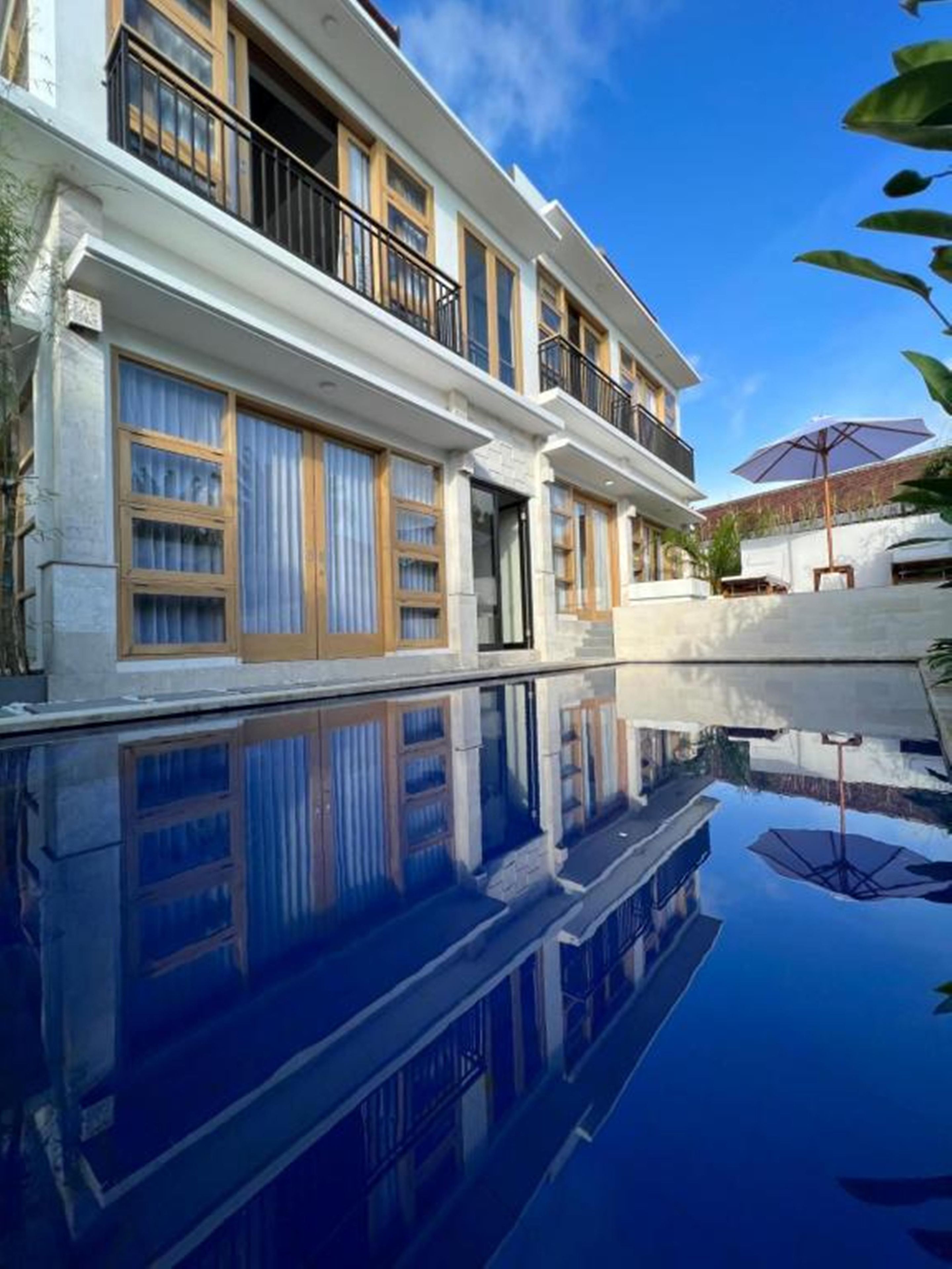 A modern building with a reflective pool, large windows, and a balcony.