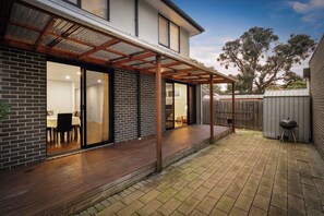 Ein modernes Haus mit überdachter Terrasse, einer Ziegelaußenwand und einem sichtbaren Innenbereich mit Essbereich.