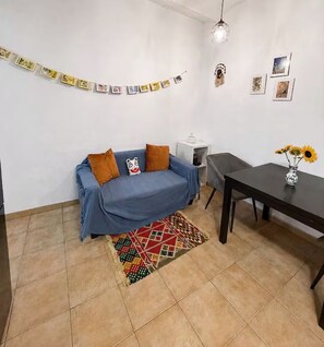 A small living area with a sofa, a rug, a table, and a vase with flowers. - Quiet 3-Bed Eixample Flat, 2 workstations, Balcony & Fast Wi-Fi (Barcelona)