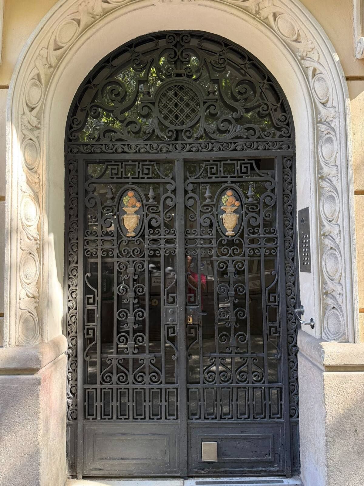 A black wrought iron gate with intricate designs and two decorative urns.