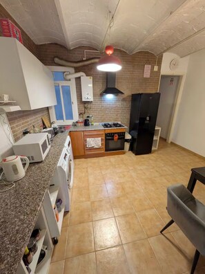 A kitchen with a central island, a stove, a refrigerator, and a microwave. - Quiet 3-Bed Eixample Flat, 2 workstations, Balcony & Fast Wi-Fi (Barcelona)