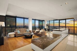 A modern living room with a sofa, chairs, a coffee table, and a kitchen area with a marble countertop. - Skyline View, Crown Casino & Free Parking (Southbank)