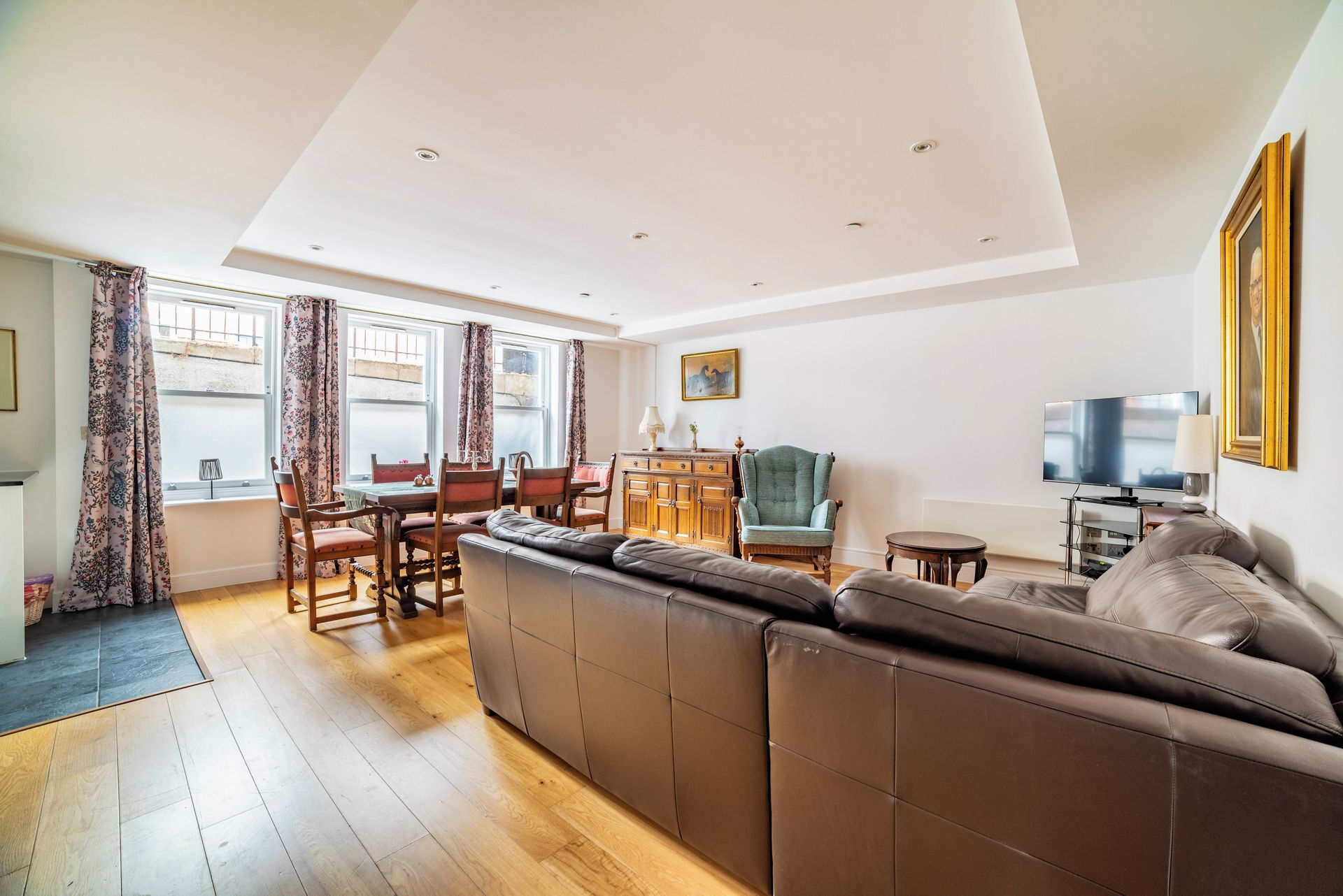 A modern living room with a sofa, dining table, chairs, and a television.