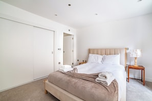Ein Hotelzimmer mit einem Bett, einem Nachttisch, einer Lampe und einer Tür.