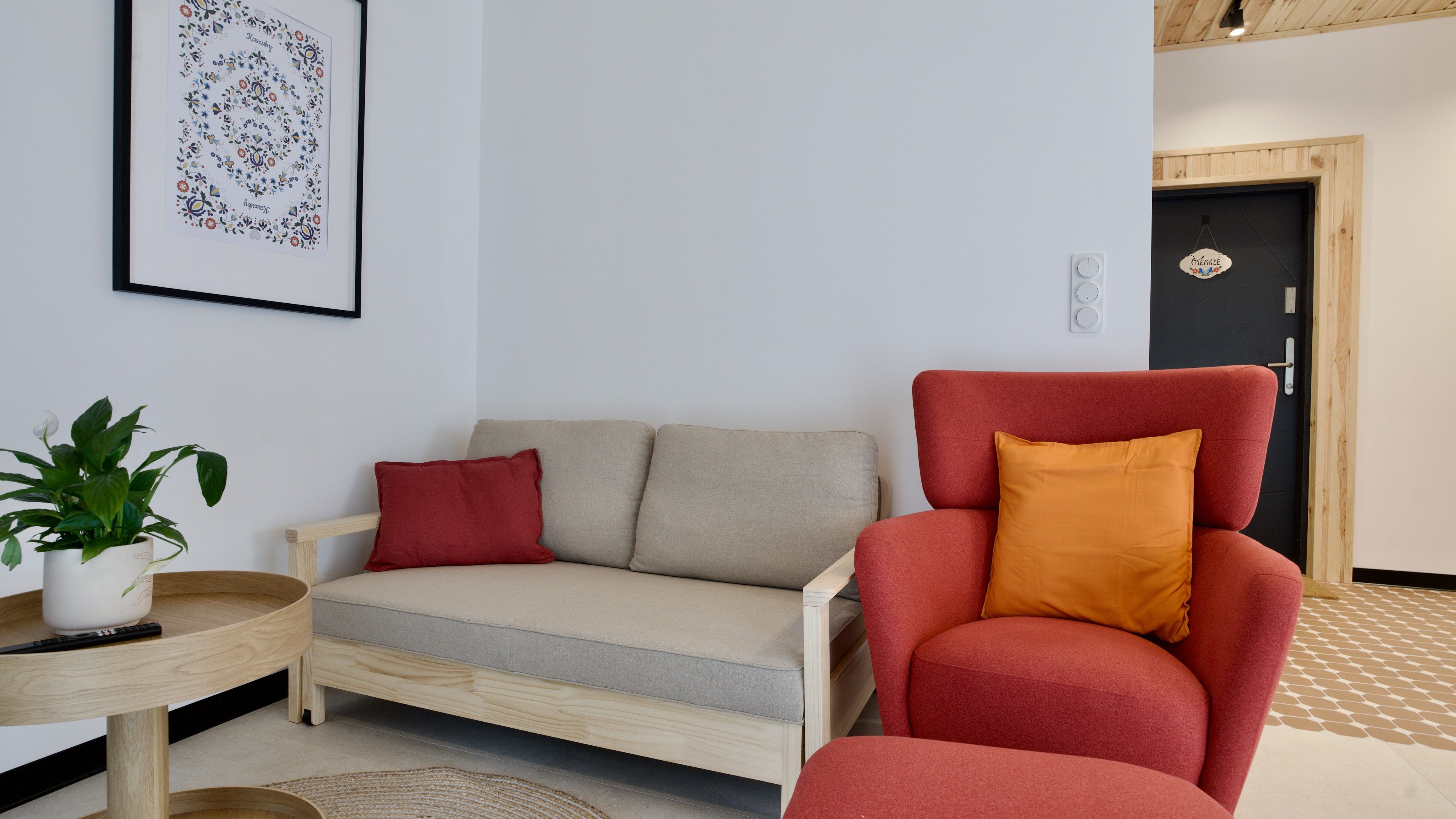Ein modernes Wohnzimmer mit einer Couch, einem Sessel und einem kleinen Tisch mit einer Pflanze.