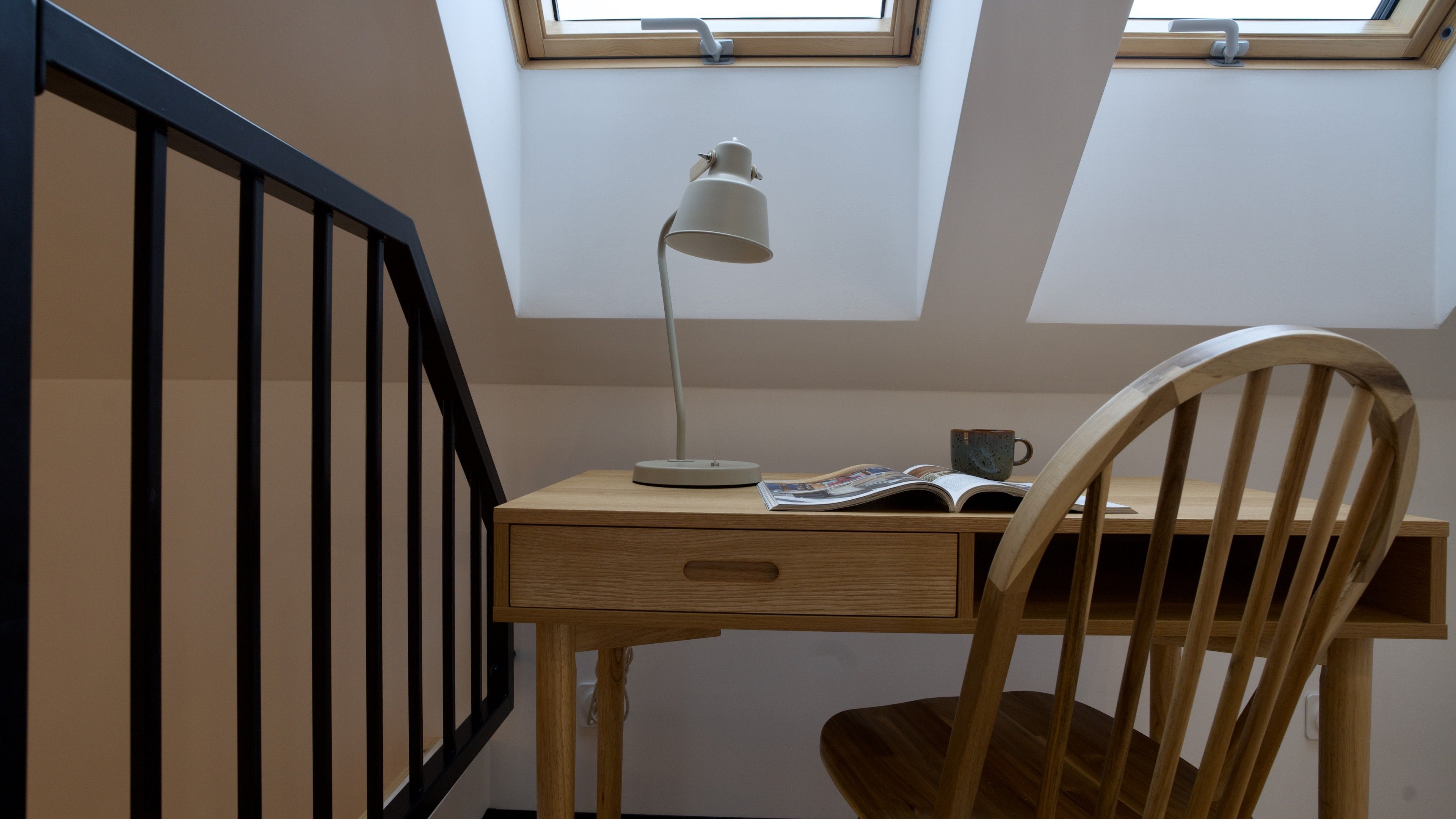 Een werkplek met een bureau, stoel, lamp en een raam.