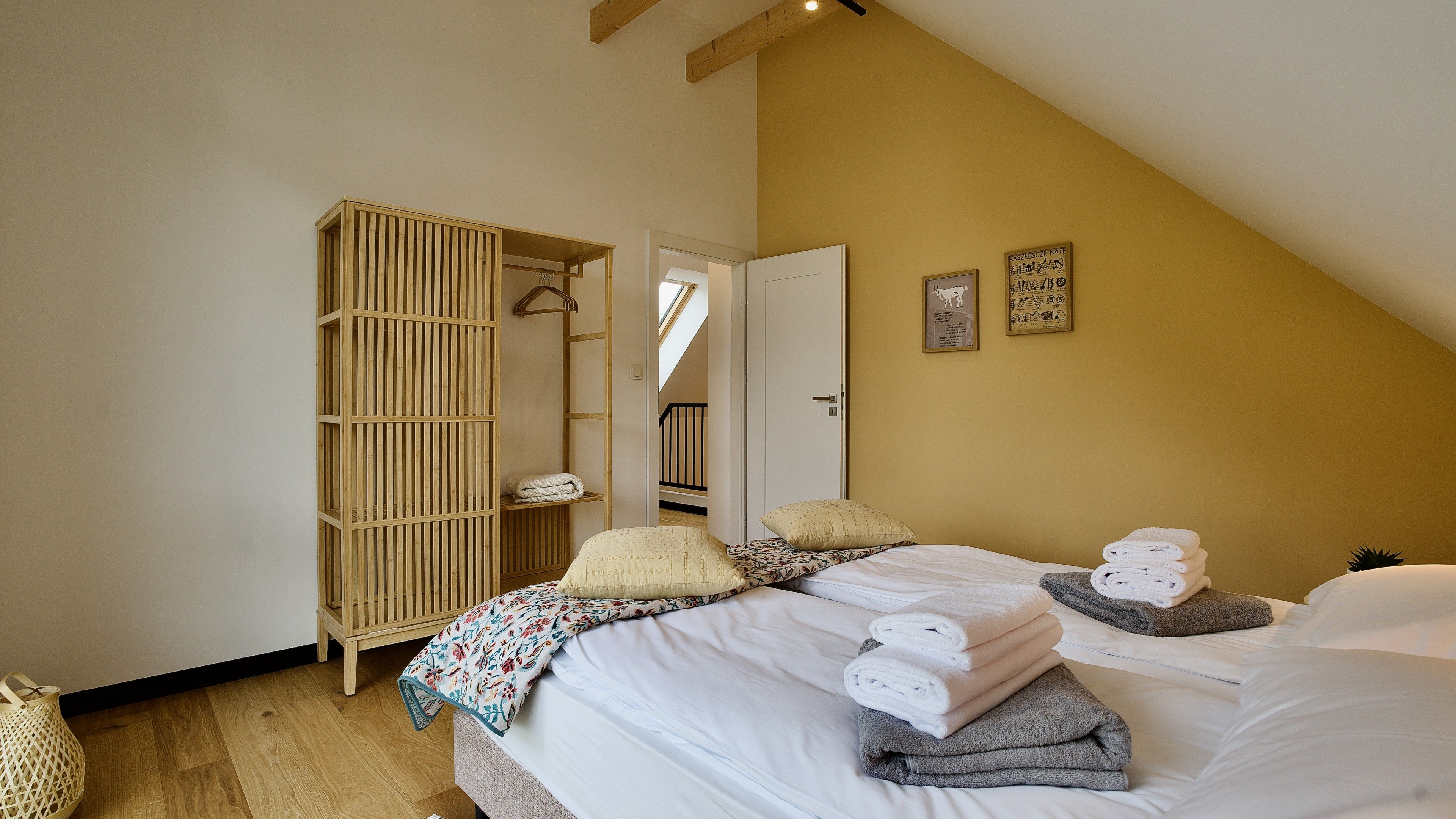 A bedroom with a bed, a wooden wardrobe, and a door leading to a staircase.