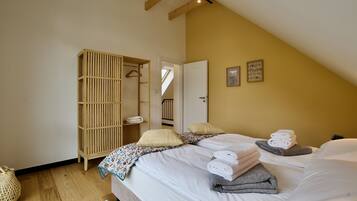 A bedroom with a bed, a wooden wardrobe, and a door leading to a staircase.