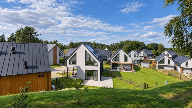 Um bairro residencial com casas modernas, gramado bem cuidado e céu claro.