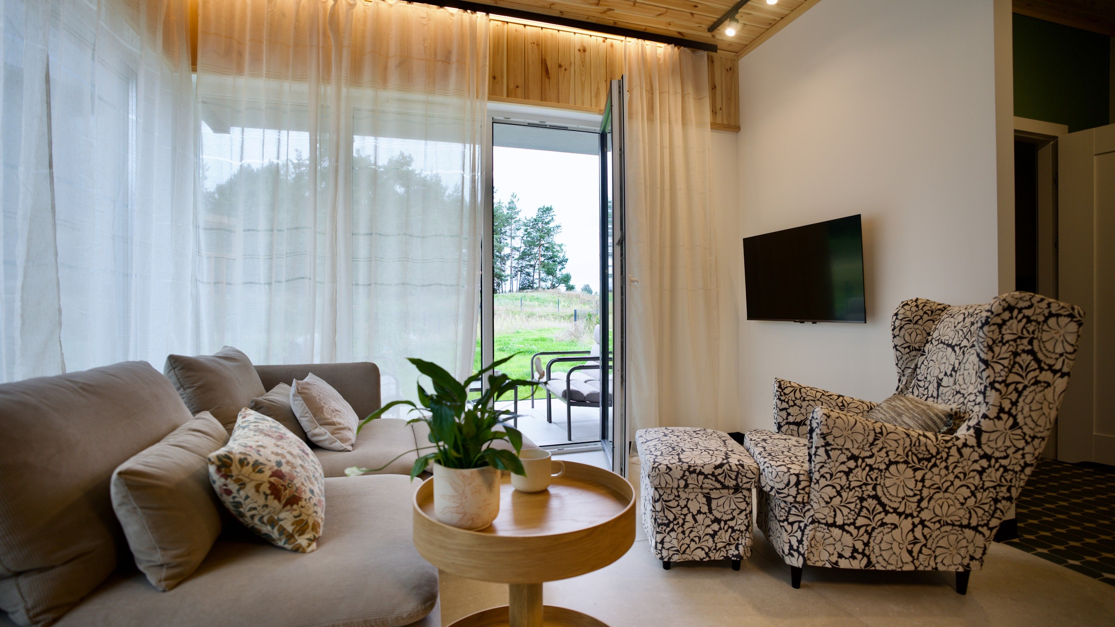 En moderne stue med sofa, lænestol og et lille bord med en plante.