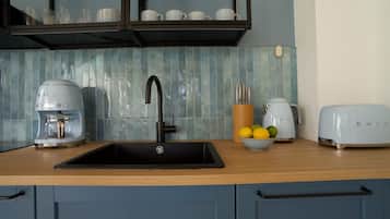 A kitchen with a sink, a coffee maker, a toaster, and a bowl of lemons.