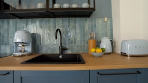 A kitchen with a sink, a coffee maker, a toaster, and a bowl of lemons.