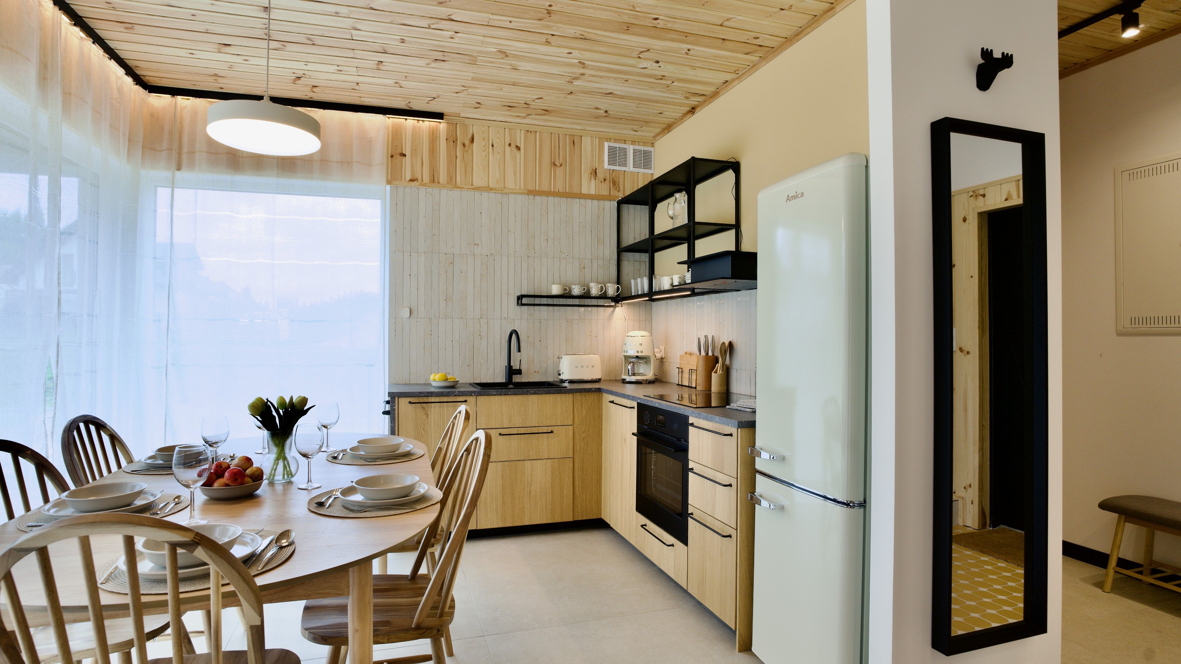 Eine moderne Küche mit Holzausstattung, einem Esstisch für vier Personen und einem großen Fenster.