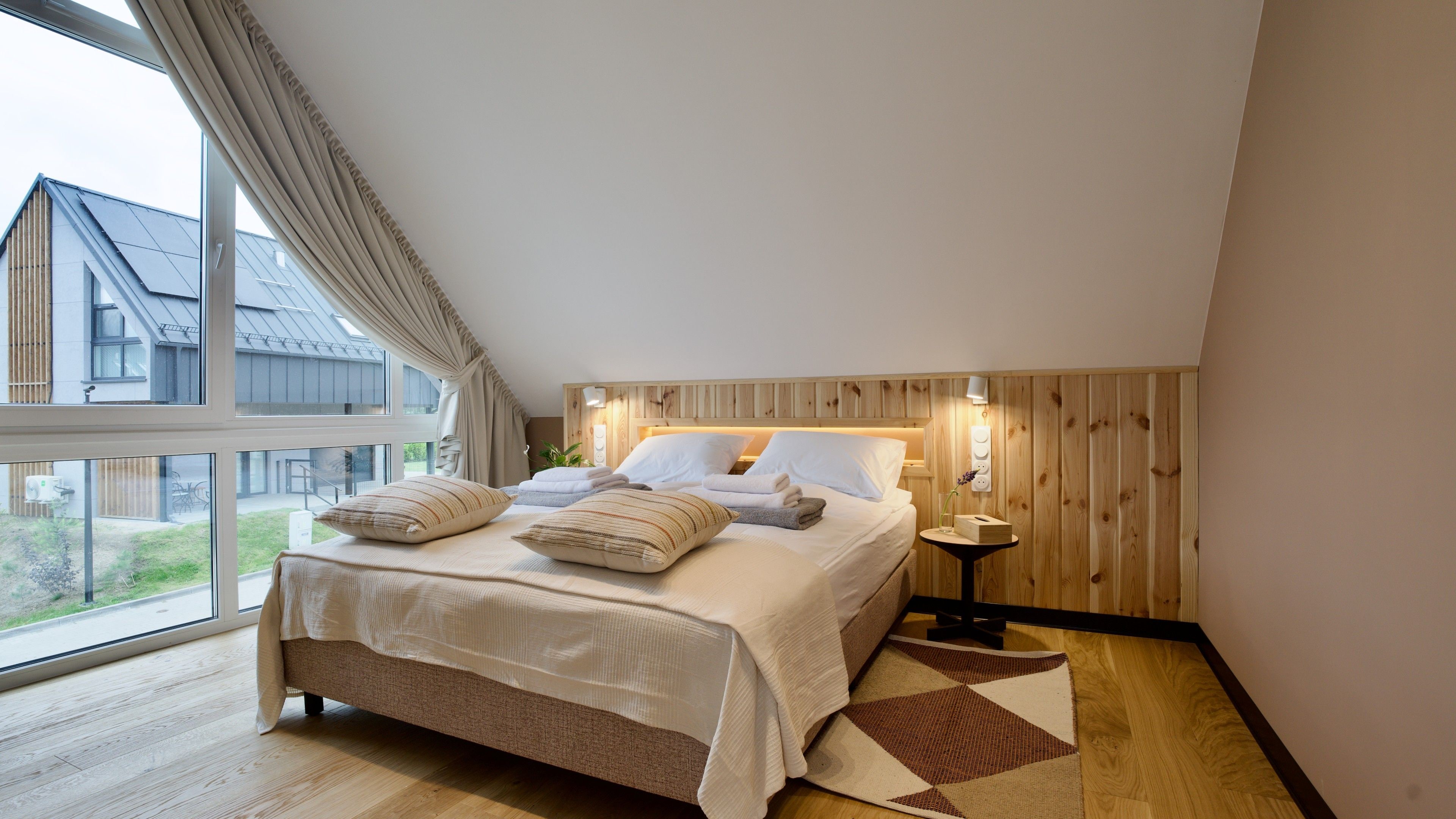 Una camera da letto con un letto grande, un comodino e vista su un edificio.