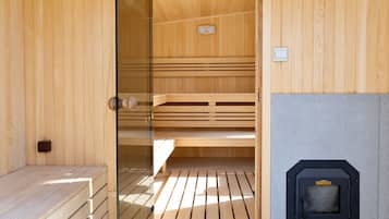 Una sala de sauna con bancos de madera, una puerta de cristal y un calentador de sauna.