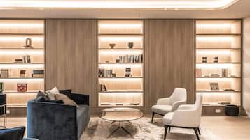 A modern living room with a blue sofa, a round coffee table, and two armchairs. There are two large bookshelves filled with books and decorative items.
