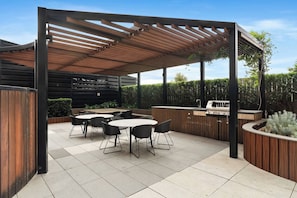 An outdoor patio with a wooden pergola, a grill station, and a seating area with tables and chairs. - Sky One 3BR, 4 Min Walk to Box Hill Station - Apartment (Box Hill)