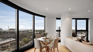 A modern interior with a dining area, a sofa, and large windows offering a city view. - Sky One 3BR, 4 Min Walk to Box Hill Station - Apartment (Box Hill)