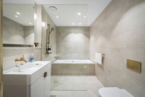 A modern bathroom with a bathtub, a shower, and a sink. - Sky One 3BR, 4 Min Walk to Box Hill Station - Apartment (Box Hill)