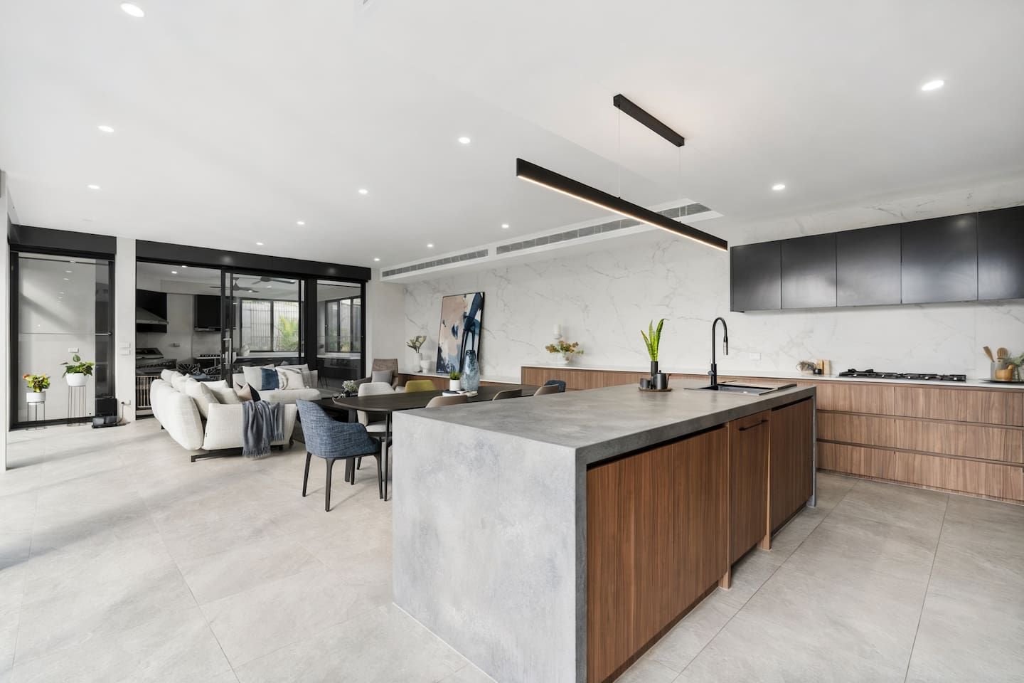 A modern kitchen with a central island, wooden cabinets, and a built-in oven.