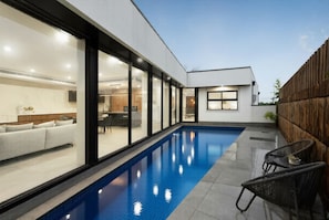 A modern house with a swimming pool, a dining area, and a living room with a sofa. - Grand Designer 5BR Home with Pool | Balwyn (Balwyn North)