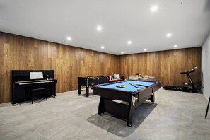 A room with a pool table, a piano, a treadmill, and a sofa. - Grand Designer 5BR Home with Pool | Balwyn (Balwyn North)
