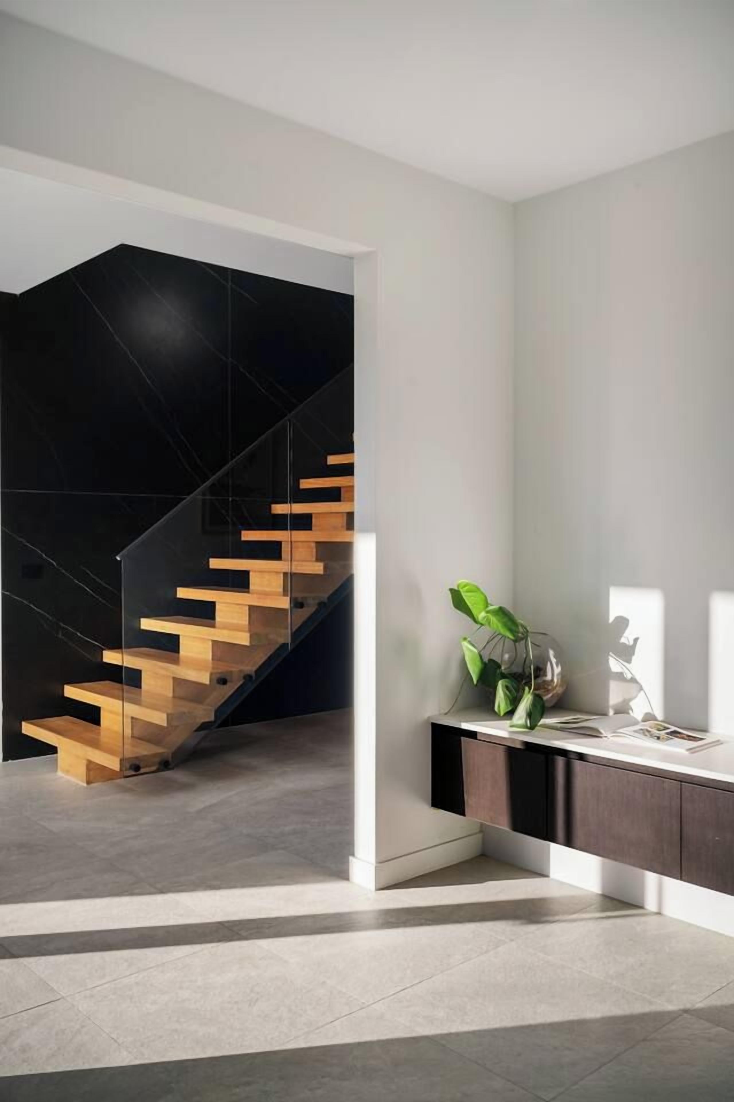 A modern interior with a staircase, a plant, and a desk area.