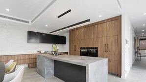 A modern kitchen with a large island, built-in ovens, and a sleek design. - Grand Designer 5BR Home with Pool | Balwyn (Balwyn North)