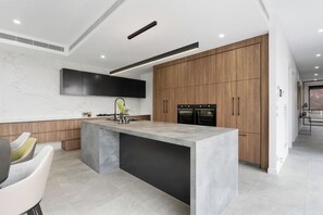A modern kitchen with a large island, built-in ovens, and a sleek design. - Grand Designer 5BR Home with Pool | Balwyn (Balwyn North)