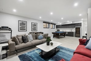 A modern living room with a sofa, coffee table, and a pool table. - Grand Designer 5BR Home with Pool | Balwyn (Balwyn North)