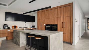 A modern kitchen with a central island, wooden cabinets, and built-in appliances.