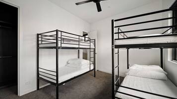Quarto com duas beliches, um ventilador de teto e uma janela.