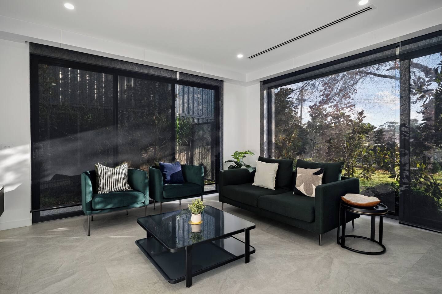 A modern living room with a sofa, two armchairs, and a coffee table.
