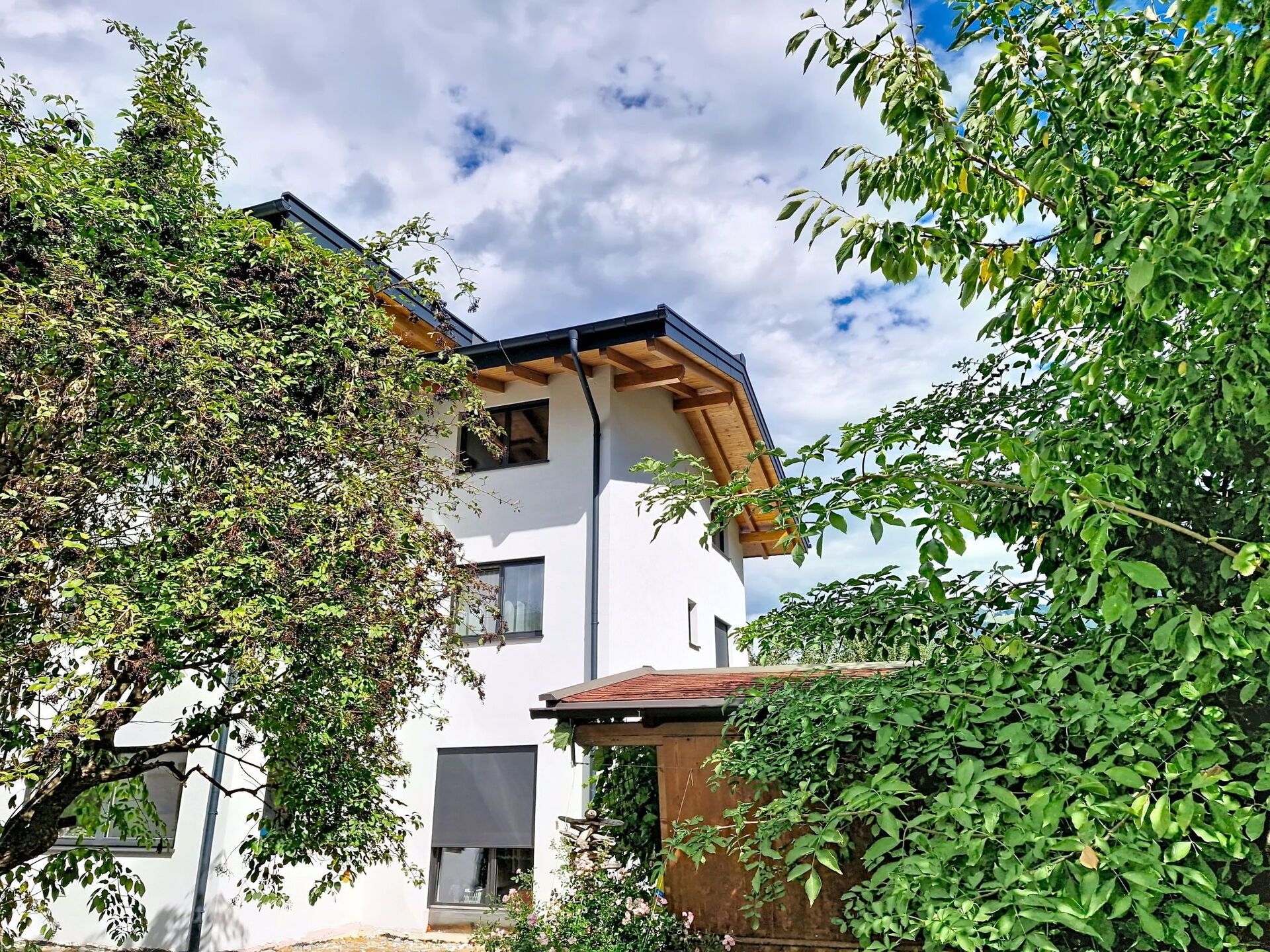 Un bâtiment moderne à deux étages, doté d’une façade blanche, de poutres en bois et d’un toit en pente.