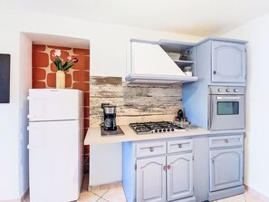 Eine kleine Küche mit einem Gasherd, einem Backofen und einem weißen Kühlschrank.