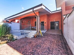 Ein Gebäude mit einer Ziegelterrasse, einer Treppe, die zu einer Tür führt, und einem Geländer.