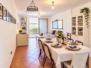 A dining area with a table set for four, a chandelier, and a view of the garden through a glass door. - Stunning  villa for 6 people with A/C, TV and pets allowed (Anzio)