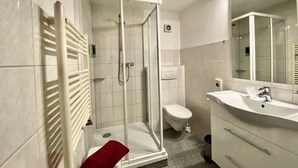 Un baño con cabina de ducha de vidrio, inodoro y lavabo con espejo.