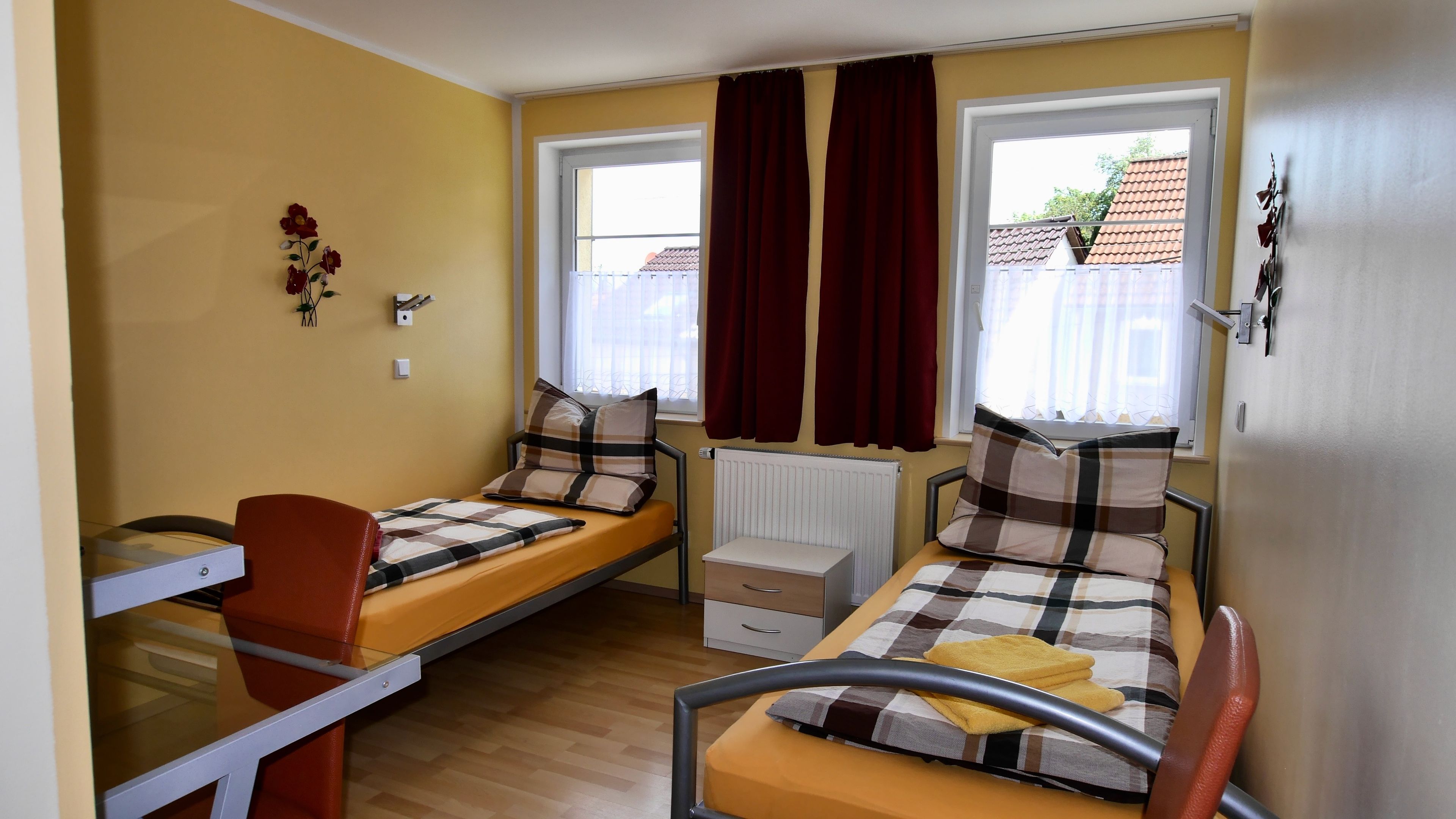 Une chambre avec deux lits simples, un bureau, une chaise et un radiateur.